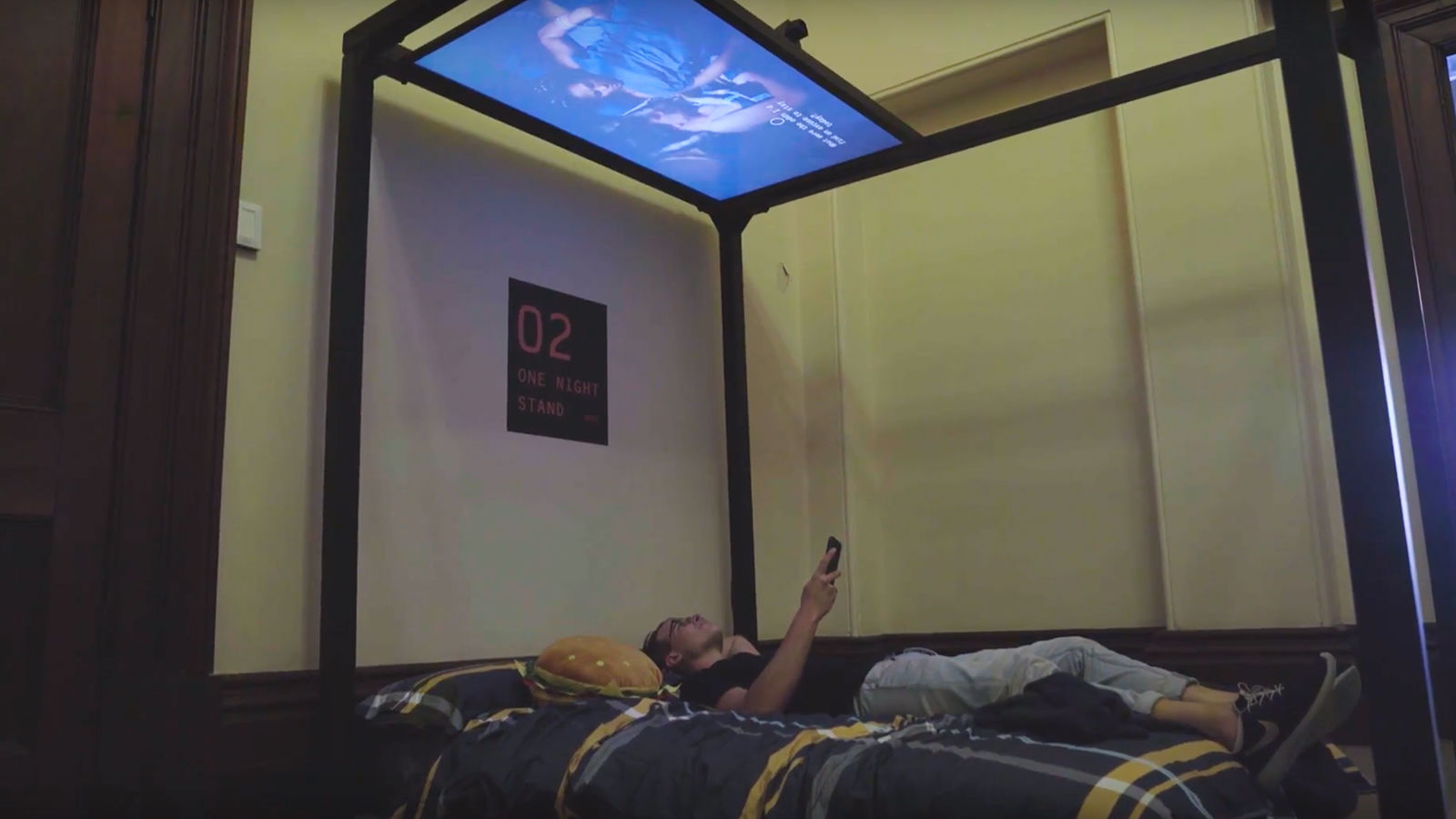 Man on bed with screen directly above their head.