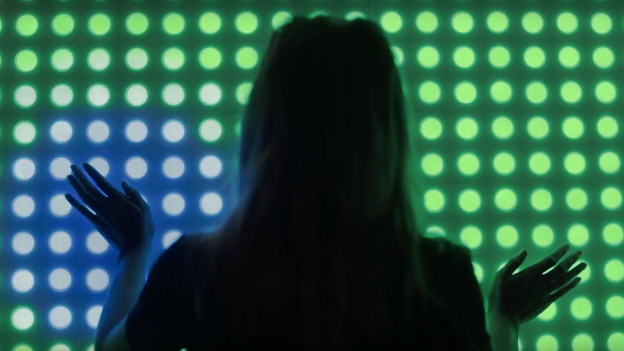 Woman touching a screen of blue and green dots.